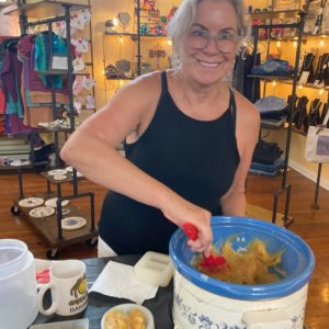 A smiling woman scooping completed soap out of a crockpot and putting it into her soap molds.