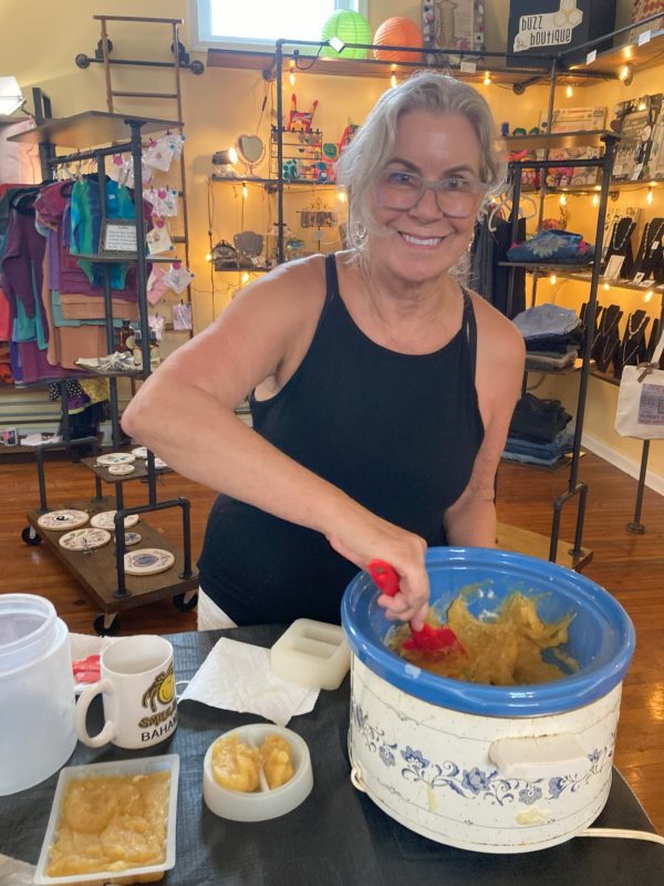 A smiling woman scooping completed soap out of a crockpot and putting it into her soap molds.