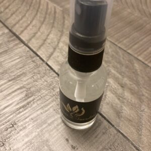 A clear glass pump bottle containing sanitizing spray.