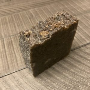 A brown bar of natural soap sitting on a wood table.