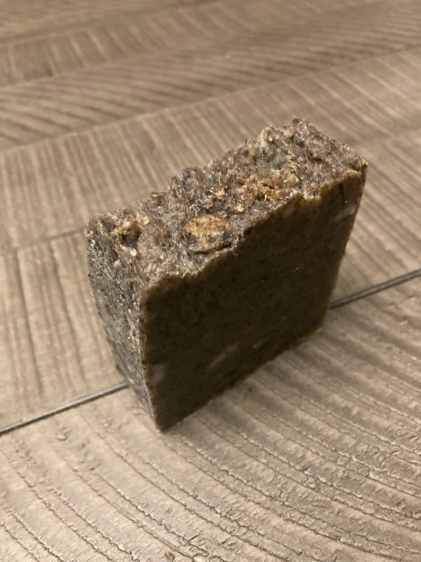 A brown bar of natural soap sitting on a wood table.