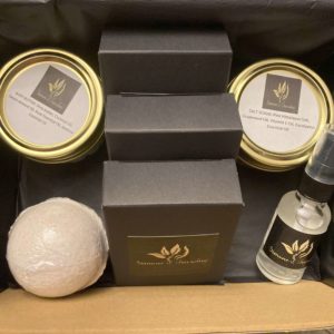 An open black box containing natural body butter, salt scrub, a lavender bath bomb and a bottle of sanitizing spray.