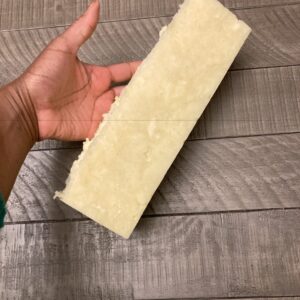 A two-pound loaf of soap being held by a hand to display the size of it. The soap is off-white in the photo.