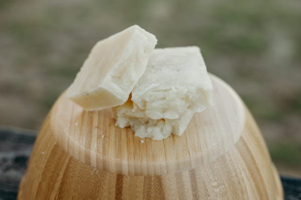 Three bars of natural light gray colored soap on an inverted wood bowl.