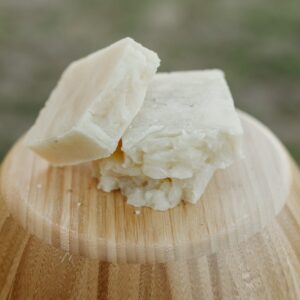 Three bars of natural light gray colored soap on an inverted wood bowl.