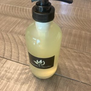 A clear glass bottle with a black pump containing liquid soap. The color of the soap is light yellow due to the eucalyptus and lemon essential oils.