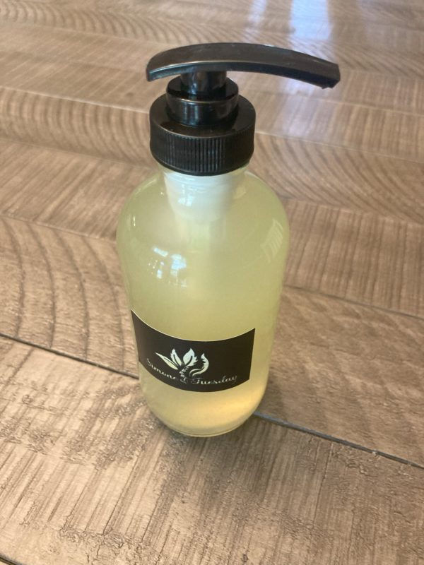 A clear glass bottle with a black pump containing liquid soap. The color of the soap is light yellow due to the eucalyptus and lemon essential oils.