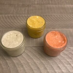 Three 4 oz glass jars filled with uniquely colored shaving soap.