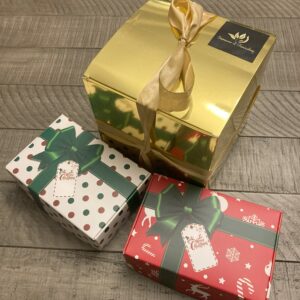 Three gift boxes. One large gold and one small green and white box and one red small box.