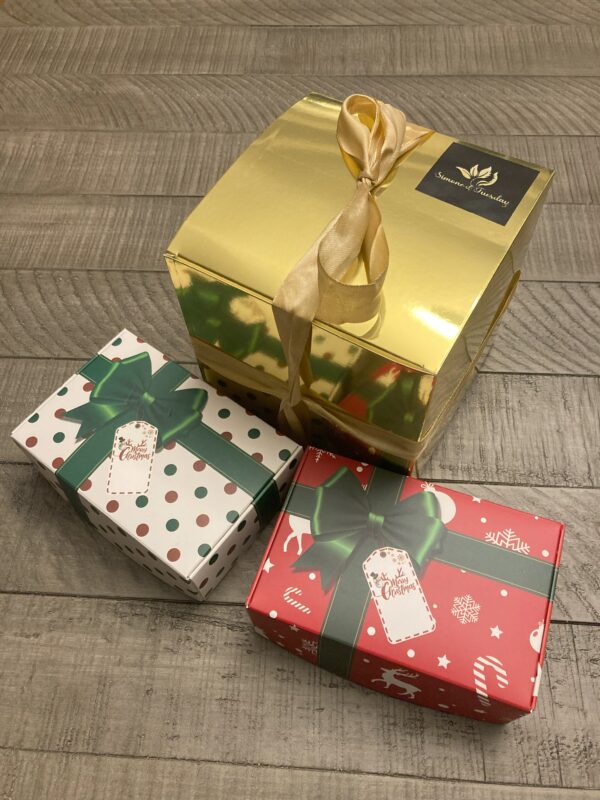 Three gift boxes. One large gold and one small green and white box and one red small box.